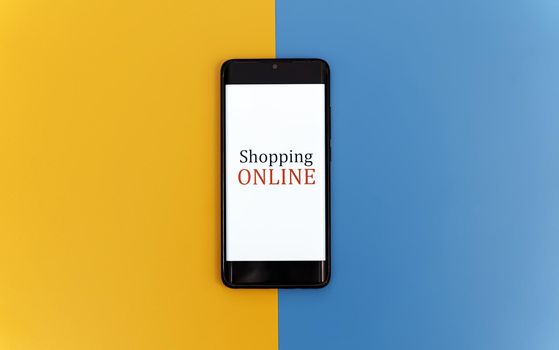 Smartphone on yellow and blue background. Online shopping concept.