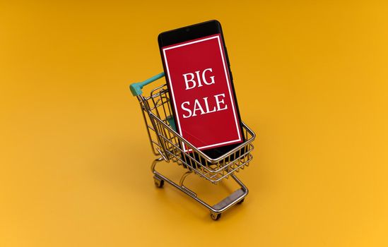 Shopping cart with smartphone. Big sale concept.