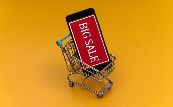 Shopping cart with smartphone. Big sale concept.