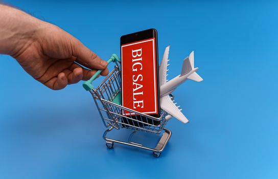 Shopping cart with plane toy. Air tickets sale concept.
