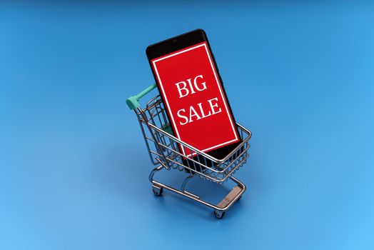 Shopping cart with smartphone. Big sale concept.