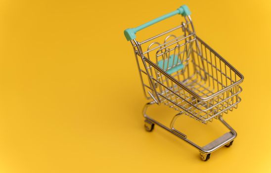 Empty shopping cart on yellow background.