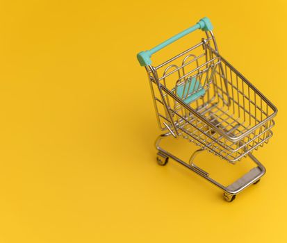 Empty shopping cart on yellow background.