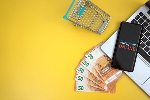 Mobile phone, shopping cart and money. Online shopping concept.