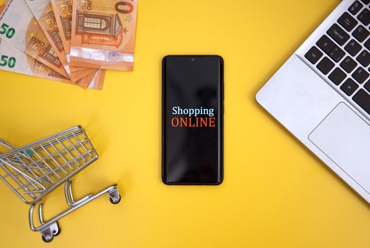 Mobile phone, shopping cart and money. Online shopping concept.