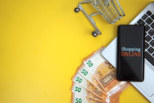 Mobile phone, shopping cart and money. Online shopping concept.