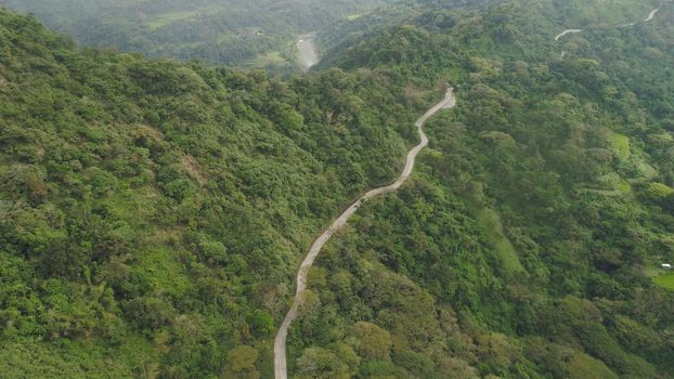 Mountain curve is a road passing along the slopes of mountains and hills covered with green forest and vegetation. Philippines, Luzon.