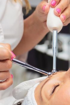 The girl is undergoing a procedure in a beauty salon. Anti-aging treatment with microcurrent drugs