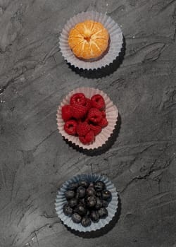 tangerine, blueberry, raspberry on grey background