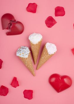 two red hearts, ice creams and rose petals on pink background