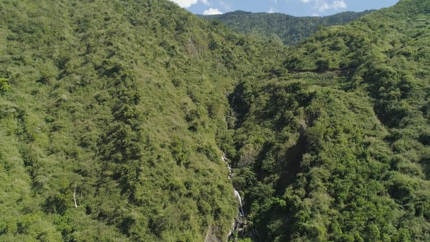 Aerial view of waterfall in the mountains of Filipino cordillera. Waterfall in the mountains. waterfall flowing on the slopes of mountains covered with tropical vegetation. Philippines, Luzon