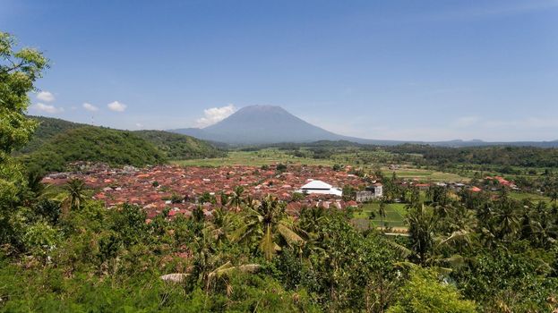 Aerial view Town near volcano Agung, rice terrace, farmlands, village, fields with crops, agricultural land of farmers. Bali, Indonesia