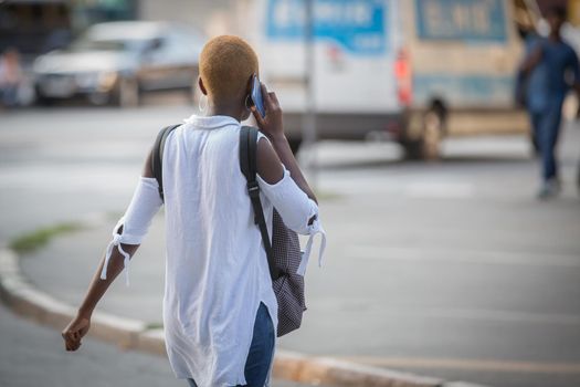 African American girl talking on a cell phone. African girl with a beautiful short fashionable hairstyle. Girl communicates using a smartphone. Foreign student. Migrant students.