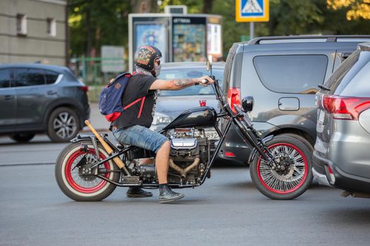 Brutal biker on a black motorcycle. Motorcyclist rides a motorcycle. Beautiful classic motorcycle. Motorcyclist in urban traffic at rush hour.