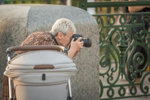 Pensioners in a city park. Retired photographer. An elderly woman takes pictures. Leisure of the elderly Active lifestyle of the elderly.