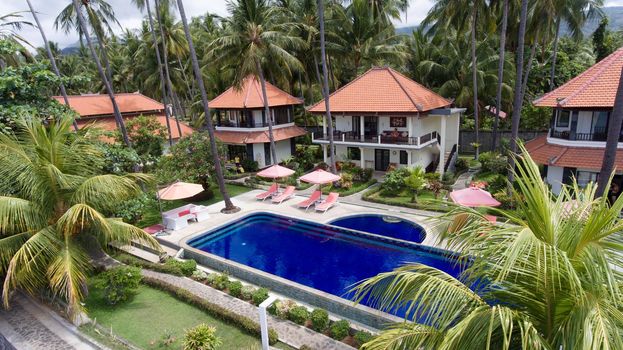 Aerial view of Luxury Hotel,resort with large bungalows by the sea with a pool among the palm trees. Bali, Indonesia. 4K video Travel concept, Aerial footage.