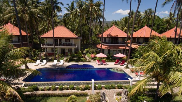 Aerial view of Luxury Hotel,resort with large bungalows by the sea with a pool among the palm trees. Bali, Indonesia. 4K video Travel concept, Aerial footage.