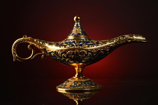 A magical ornate brass oil lamp over an atmospheric red and black gradient background.
