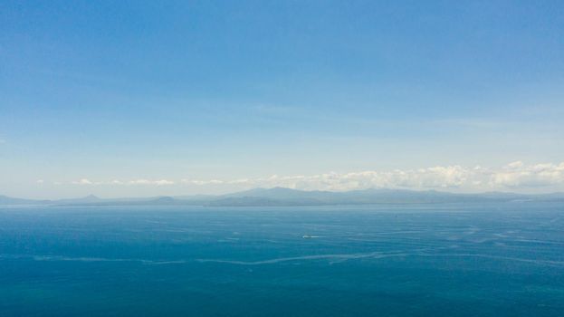 Blue sea and the tropical island of Basilan with mountains. Seascape with a tropical island. Zamboanga, Mindanao, Philippines.