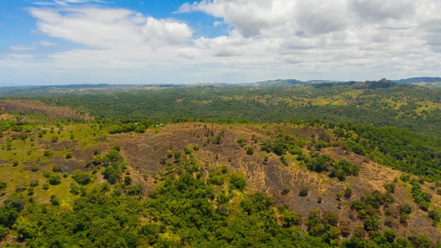 Landscape with green hills and meadows under a blue sky, view from above. Bohol, Philippines.