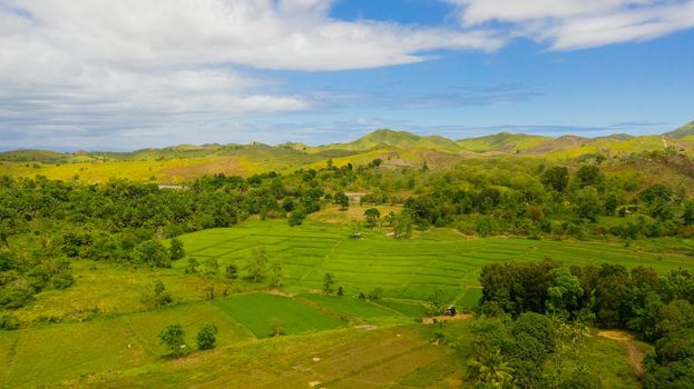 Hills and mountains covered with green grass against a background of blue sky and clouds. Bohol, Philippines. Summer landscape.