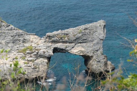 Rock in the ocean at Atuh beach on Nusa Penida island, Indonesia. Rocks in a blue sea lagoon with breaking waves. Travel concept