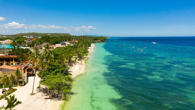 Tropical sandy beach with palm trees and turquoise clear waters. Alona beach, Panglao island, Philippines.