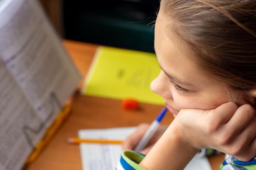 Close-up of a girl doing homework, a girl lost in thought distracted from the task