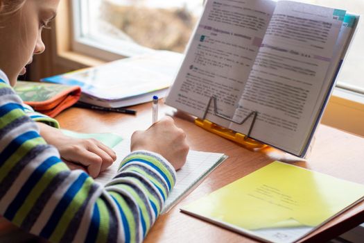 Girl at home in front of the window doing homework