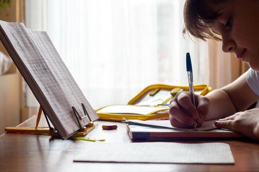 Girl doing homework sitting at the table by the window