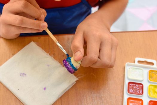 A girl paints a figurine made of salt dough with a brush