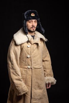 Portrait of a man of Caucasian appearance in a Soviet officer's fur hat and army sheepskin coat
