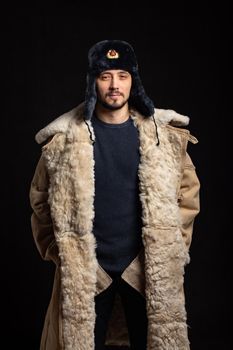 Portrait of a confident man of Caucasian appearance in a Soviet officer fur hat and army sheepskin coat