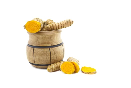 Fresh raw turmeric roots and a small wooden pot isolated on white background
