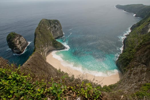 Beach with turquoise water among the rocks. Tropical beach among rocky cliffs. Karang Dawa, Manta Bay or Kelingking Beach on Nusa Penida Island, Bali, Indonesia.Travel concept.