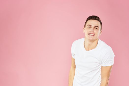 Emotional man gesturing with his hands white t-shirt pink isolated background. High quality photo