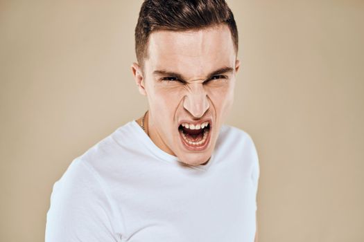 Man with displeased facial expression emotions white t-shirt gestures with hands beige background. High quality photo