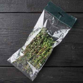 Fresh juicy Thyme in market pack set, on black wooden table background, top view flat lay
