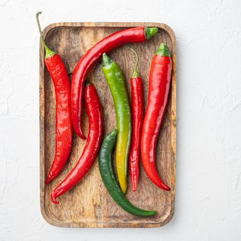 Red and green chili pepper set, on wooden tray, on white background, top view flat lay