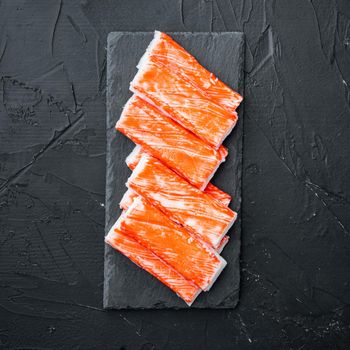 Crab sticks seafood semi finished fish mince with blue swimming crab set, on stone board, on black background, top view flat lay