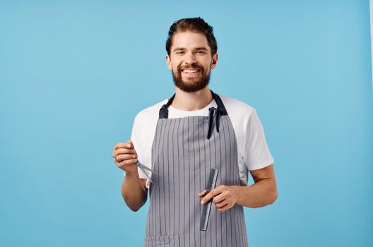 man hairdresser in gray apron scissors comb barbershop thick beard brunette. High quality photo