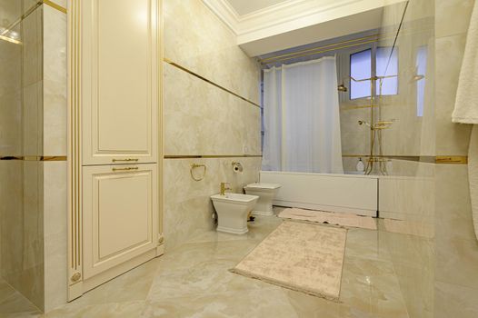 Modern luxury beige and golden bathroom with toilet, bidet and bathtub