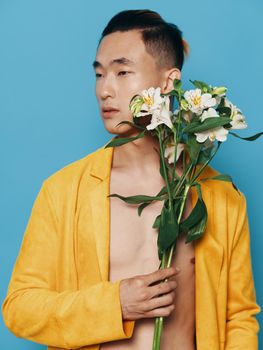 man with bouquet of white flowers on blue background and yellow coat cropped view. High quality photo