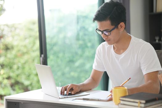 asian young teenage student man teenager entrepreneur working with computer studying learning online at home. e-learning webinar meeting. social distance in covid pandemic