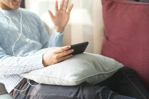 young asian man wearing earphones talking on video call meeting using smart mobile phone