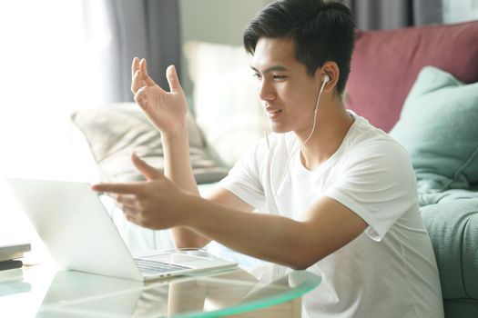 asian young teenage student man entrepreneur wear earphones working by video call conference studying learning online at home. e-learning webinar meeting. social distance in covid pandemic