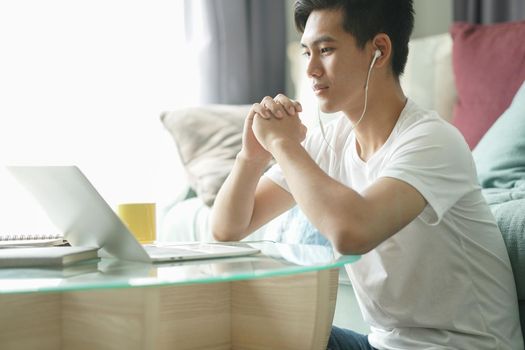 asian young student man teenager entrepreneur wear earphones working with computer studying learning online at home. e-learning webinar meeting. social distance in covid pandemic
