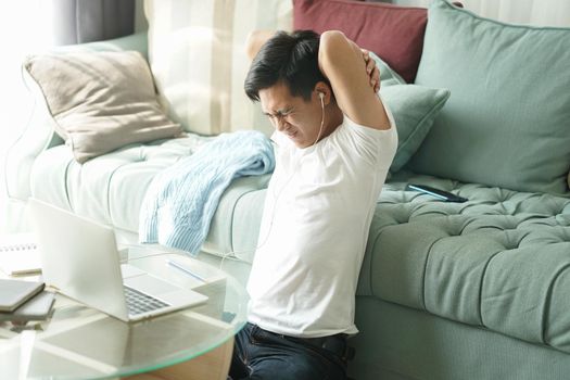 asian young student man teenager entrepreneur wear earphones stretching feeling tired bored sleepy while working with computer studying learning online at home. e-learning education