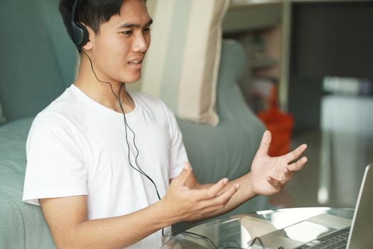 asian young teenage student man entrepreneur wear headphones working by video call conference studying learning online at home. e-learning webinar meeting. social distance in covid pandemic
