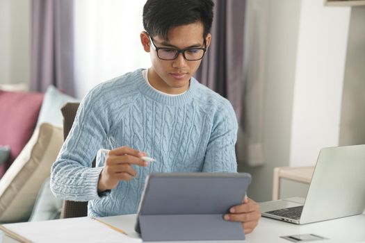 asian young teenage student man teenager entrepreneur working with tablet studying learning online at home. e-learning webinar meeting. social distance in covid pandemic